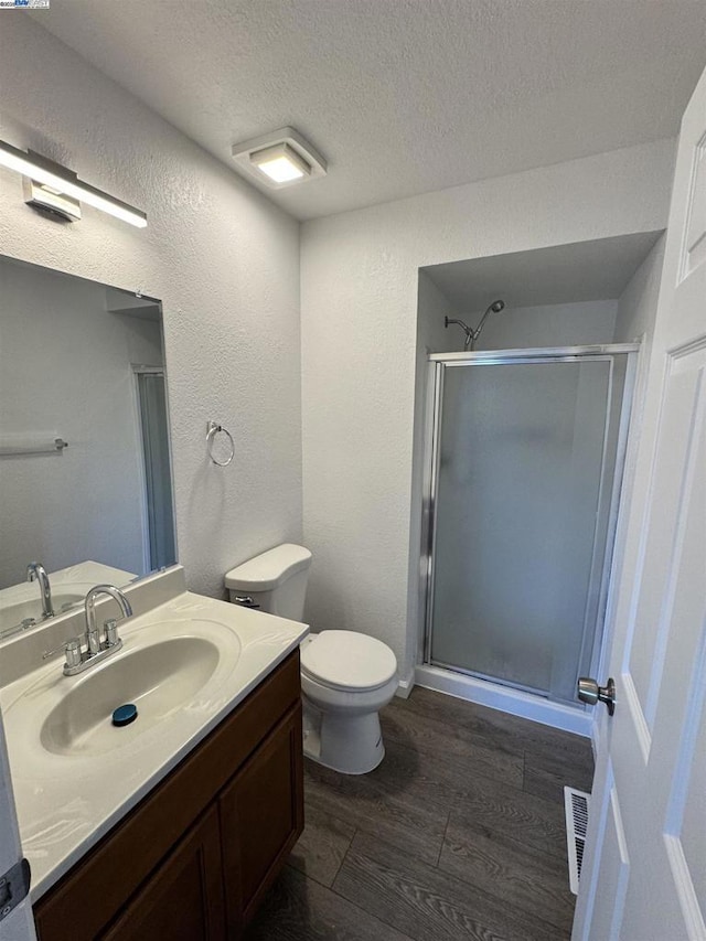 bathroom featuring an enclosed shower, wood-type flooring, vanity, and a textured ceiling