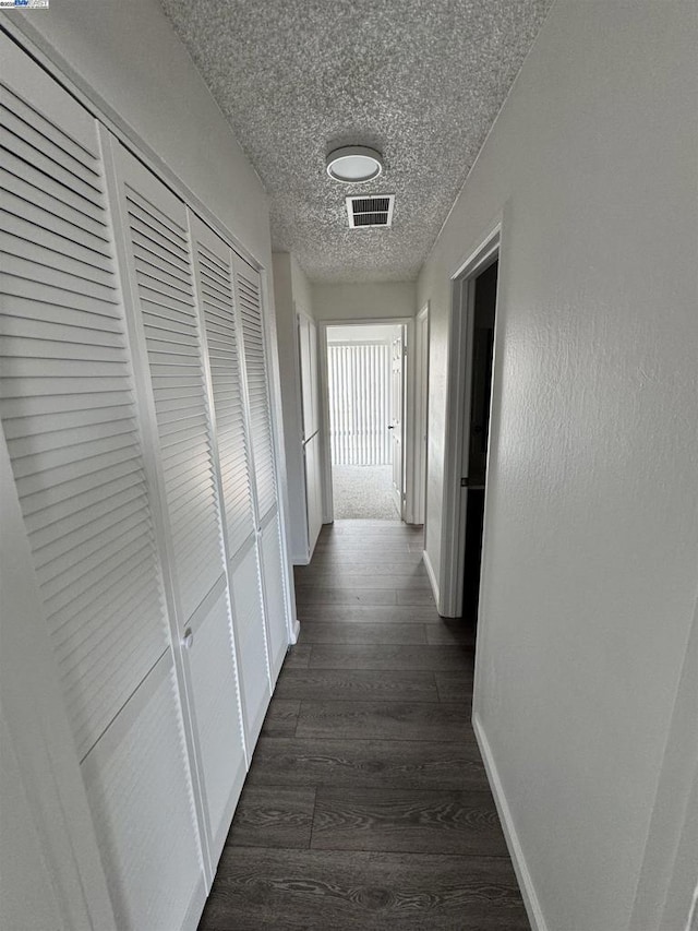 hallway featuring a textured ceiling and dark hardwood / wood-style flooring