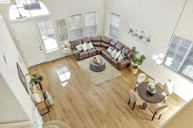 living room with hardwood / wood-style floors, a towering ceiling, and a notable chandelier