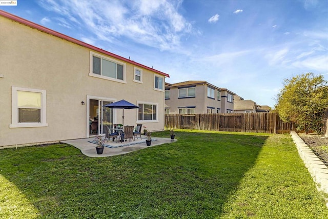 rear view of house featuring a yard and a patio