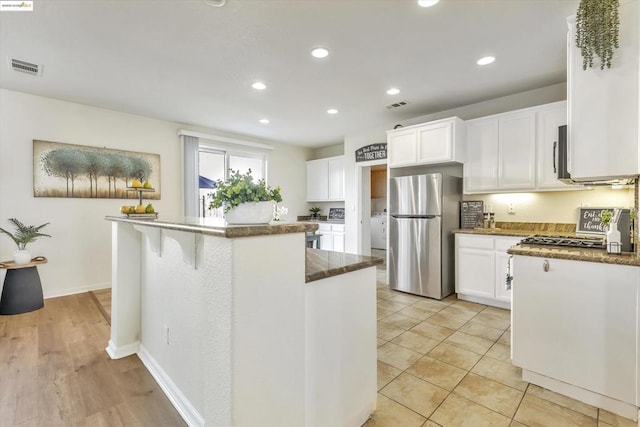 kitchen with washer / dryer, appliances with stainless steel finishes, a center island, and white cabinets