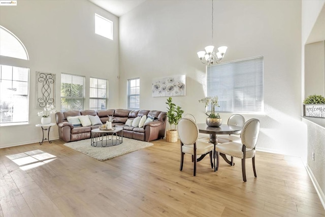 living room featuring a notable chandelier, light hardwood / wood-style flooring, and a high ceiling