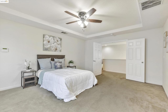 carpeted bedroom with a raised ceiling and ceiling fan