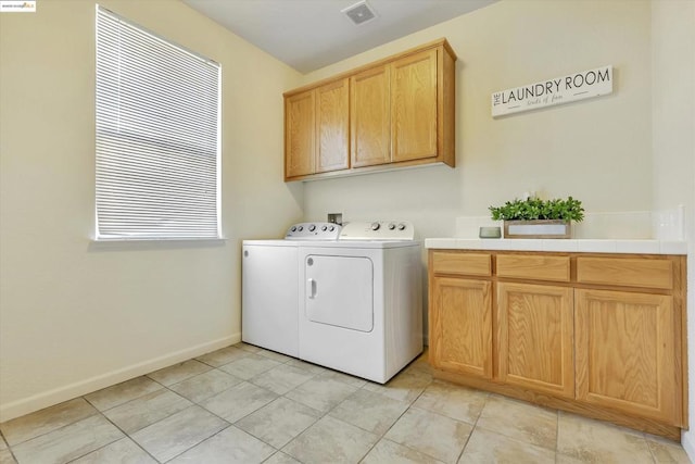 laundry area featuring light tile patterned floors, washer and clothes dryer, and cabinets