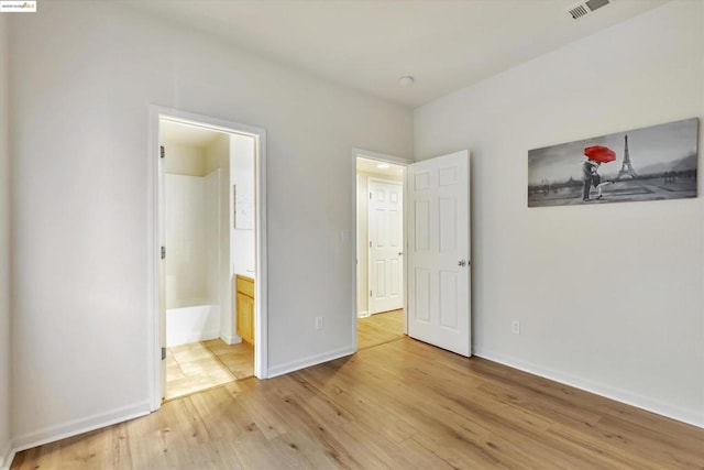 unfurnished bedroom with connected bathroom and light hardwood / wood-style floors