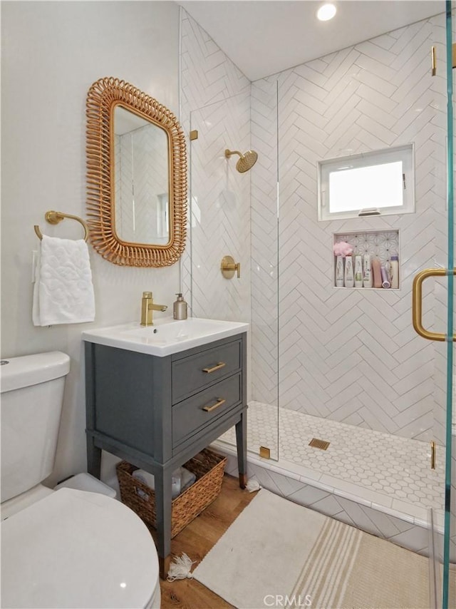 bathroom with vanity, wood-type flooring, toilet, and a shower with shower door