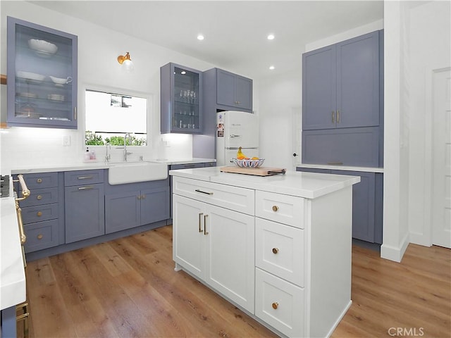 kitchen with a kitchen island, sink, white fridge, and light hardwood / wood-style flooring