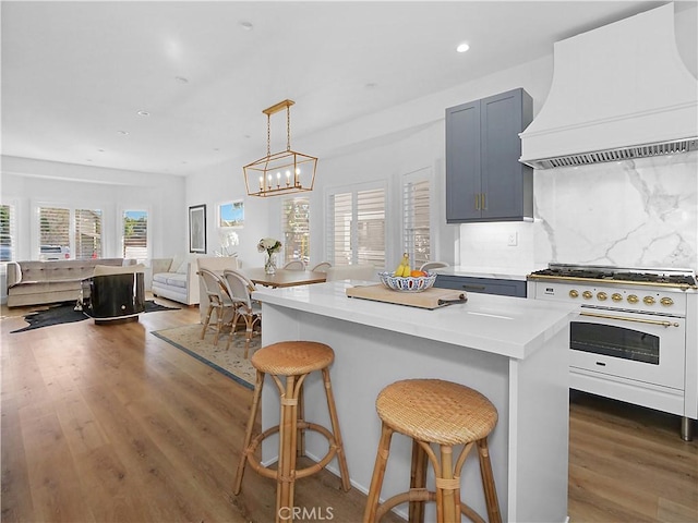 kitchen featuring premium range hood, dark wood-type flooring, a breakfast bar, decorative backsplash, and white range oven