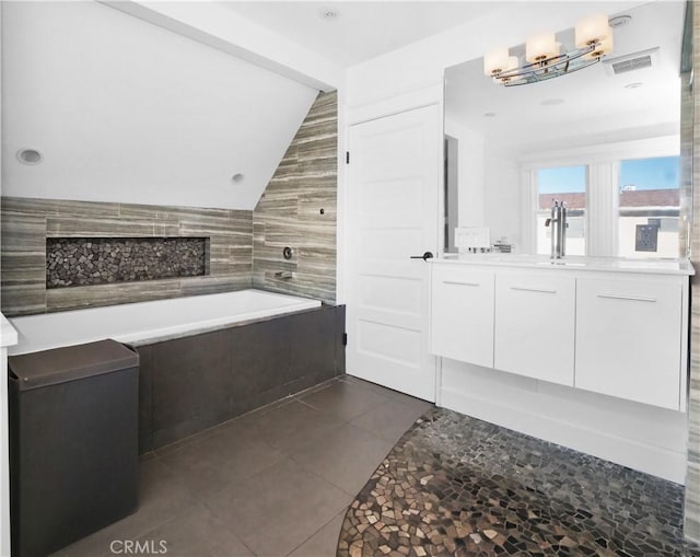 bathroom with tile patterned flooring, vanity, tiled tub, and tile walls