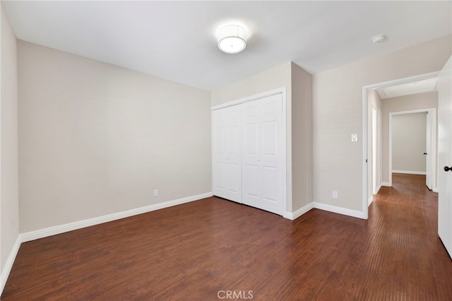 unfurnished bedroom featuring dark wood-type flooring and a closet