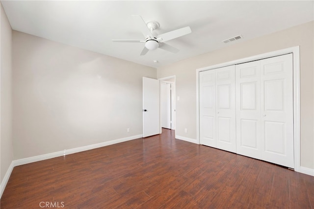 unfurnished bedroom with dark wood-type flooring, ceiling fan, and a closet