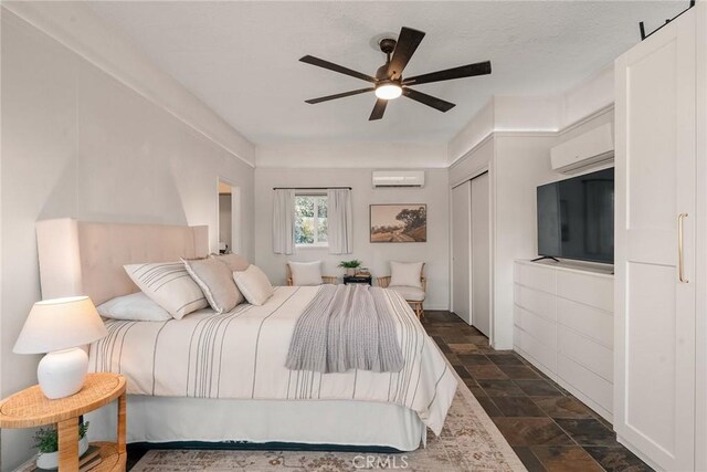 bedroom with ceiling fan, a wall mounted AC, and a closet