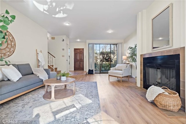 living room with a tiled fireplace and wood-type flooring