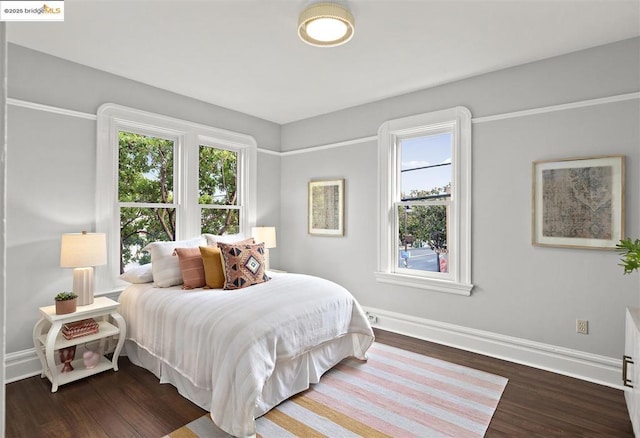 bedroom with multiple windows and dark hardwood / wood-style flooring