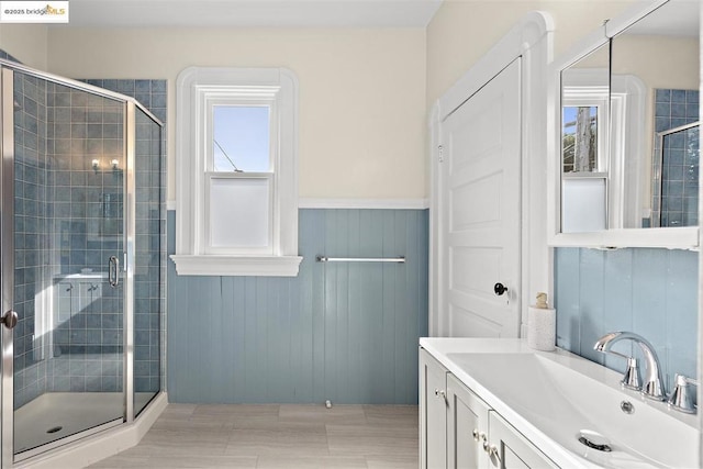 bathroom with vanity, a shower with door, a healthy amount of sunlight, and wood walls