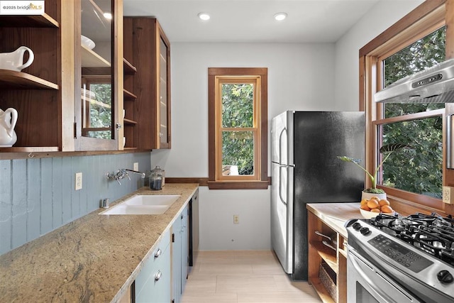 kitchen featuring light stone counters, sink, a healthy amount of sunlight, and appliances with stainless steel finishes