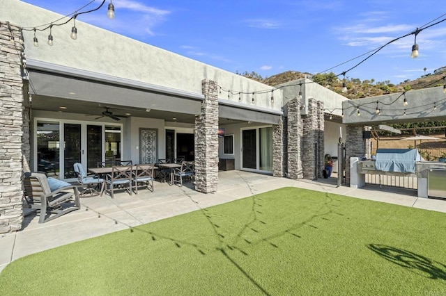 rear view of property with ceiling fan, a yard, and a patio