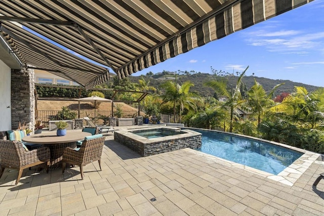 view of swimming pool with an in ground hot tub, a mountain view, and a patio