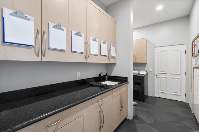 kitchen featuring light brown cabinetry, washer / dryer, sink, and dark stone countertops