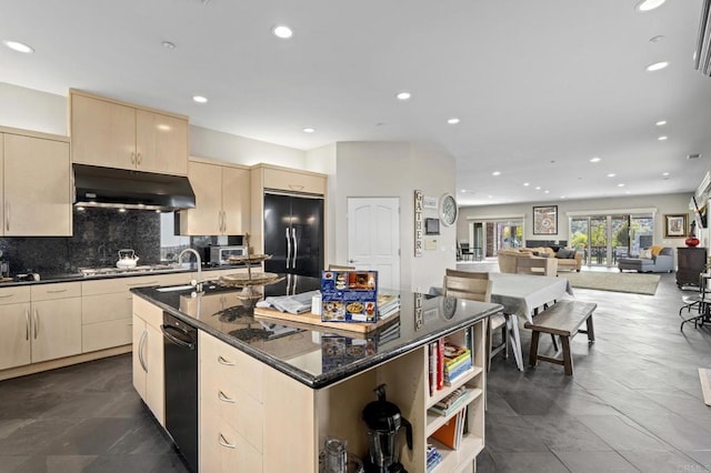 kitchen featuring tasteful backsplash, dark stone countertops, built in fridge, stainless steel gas stovetop, and a kitchen island with sink