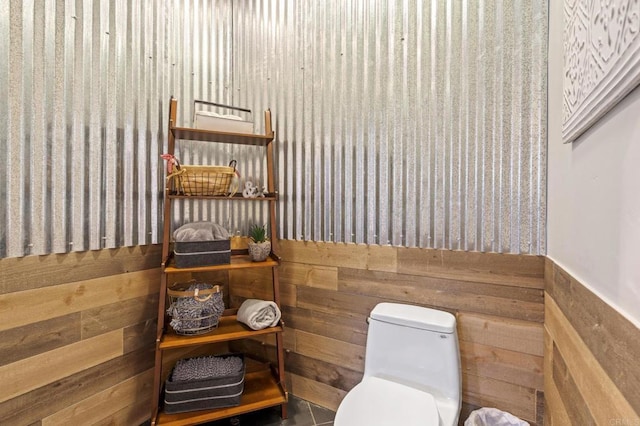 bathroom featuring wooden walls, tile patterned floors, and toilet