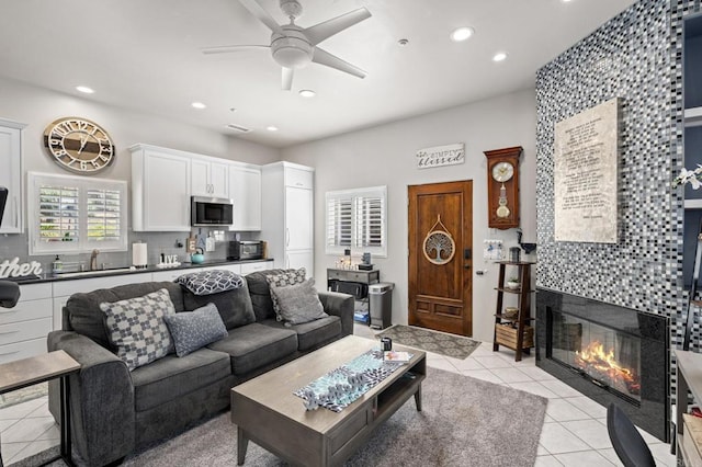 tiled living room with a tiled fireplace and ceiling fan