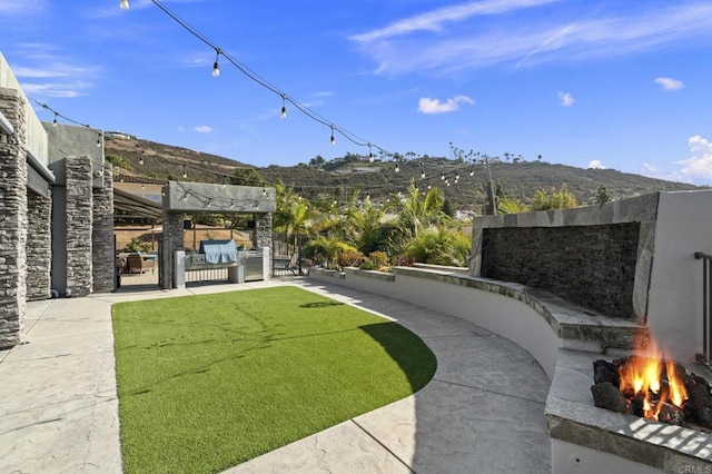 view of yard with a mountain view, a patio area, and an outdoor living space with a fire pit