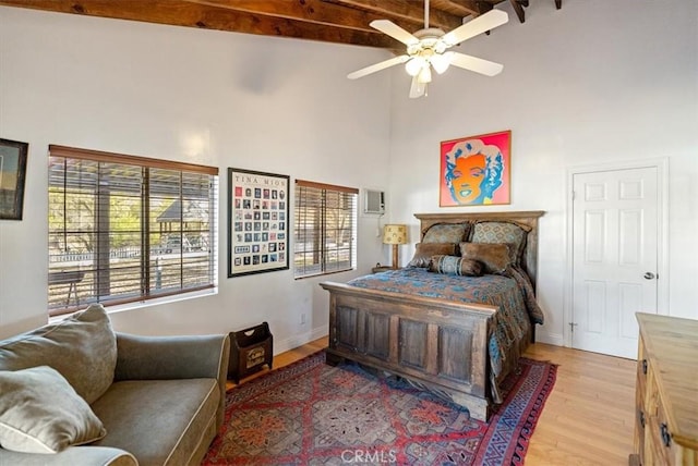 bedroom with ceiling fan, high vaulted ceiling, beam ceiling, and light hardwood / wood-style flooring