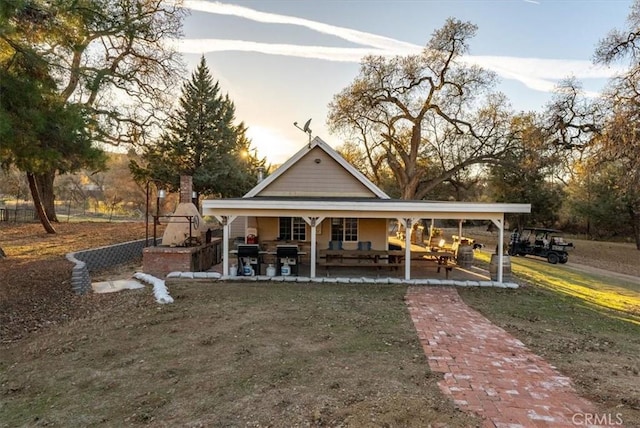 back house at dusk with a patio area and a lawn