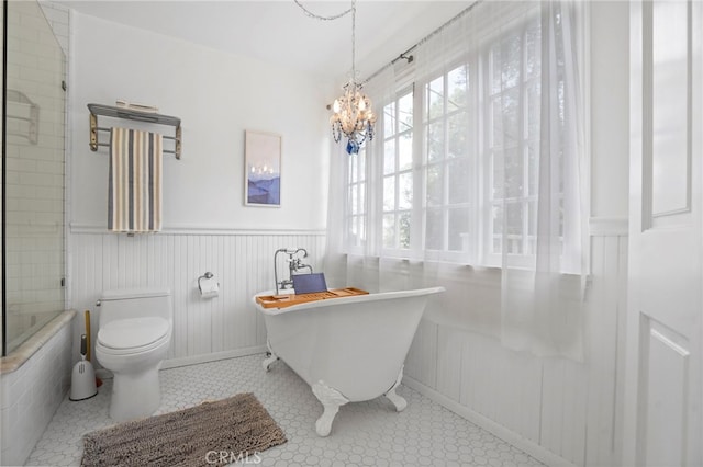 bathroom featuring a notable chandelier, tiled bath, and toilet