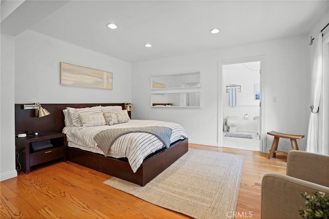 bedroom with ensuite bathroom and hardwood / wood-style floors