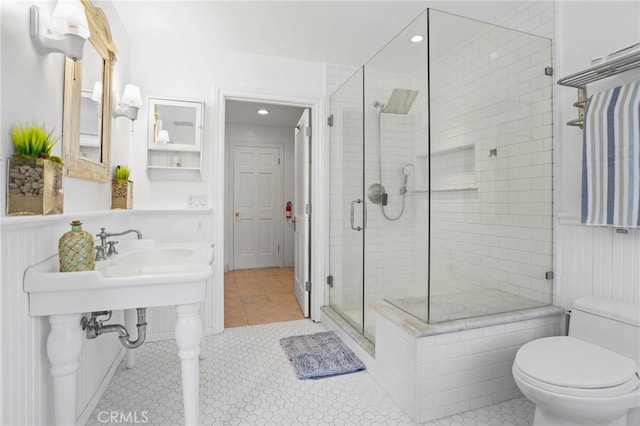 bathroom featuring a shower with door, tile patterned floors, and toilet