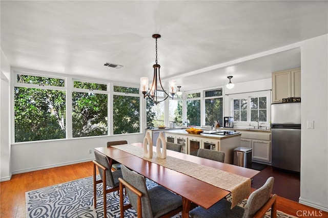 dining space featuring an inviting chandelier, sink, and hardwood / wood-style floors