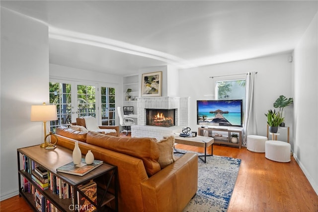 living room featuring french doors, a fireplace, hardwood / wood-style floors, and a wealth of natural light