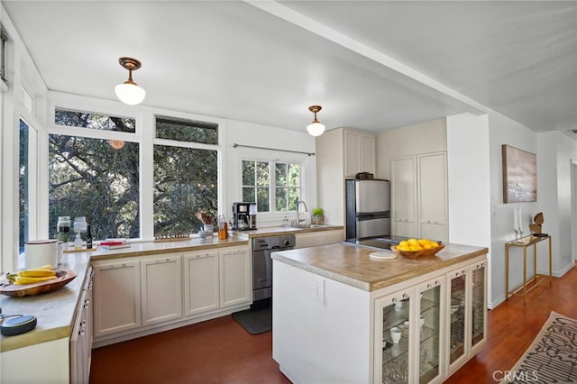 kitchen featuring dark hardwood / wood-style floors, white cabinetry, sink, hanging light fixtures, and stainless steel appliances