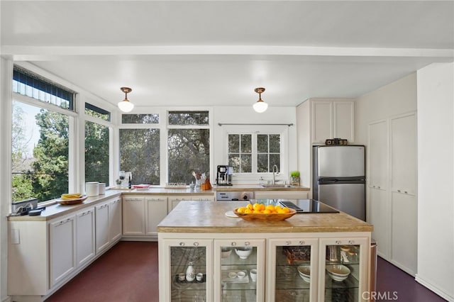 kitchen featuring dishwasher, white cabinetry, sink, stainless steel fridge, and black electric cooktop