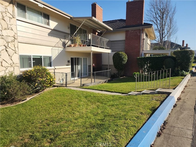 back of house featuring a balcony and a yard