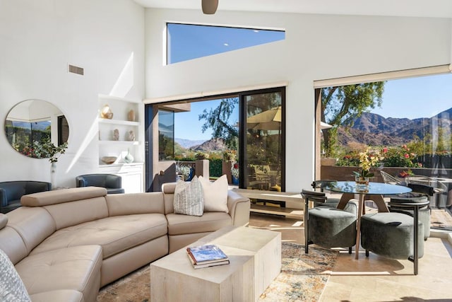 living room with a mountain view, built in features, high vaulted ceiling, and a healthy amount of sunlight