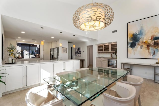 tiled dining area featuring a towering ceiling, beverage cooler, and sink