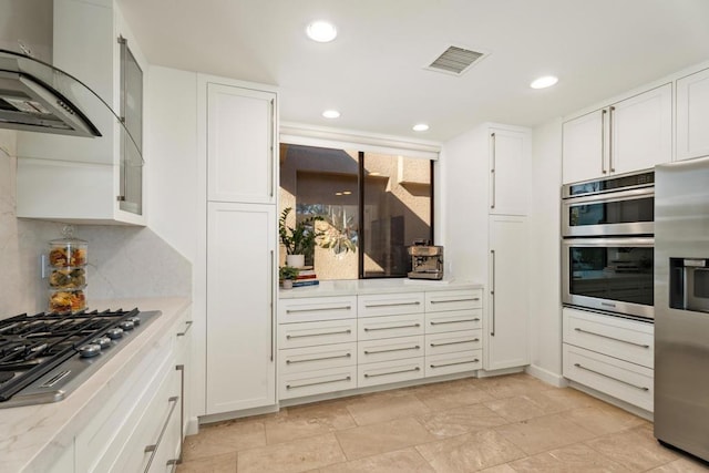 kitchen featuring white cabinetry, stainless steel appliances, wall chimney exhaust hood, and decorative backsplash