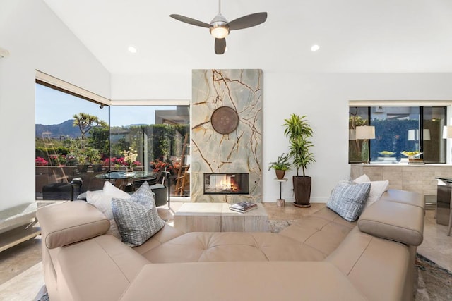 living room featuring ceiling fan, a fireplace, a mountain view, and vaulted ceiling