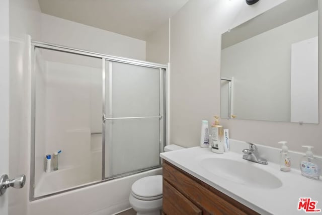 full bathroom featuring vanity, shower / bath combination with glass door, and toilet