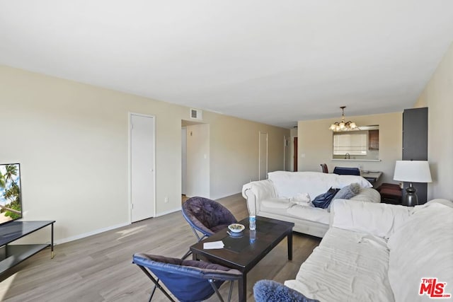 living room featuring a chandelier and light wood-type flooring