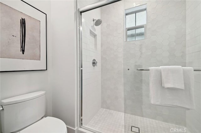 bathroom with a shower with shower door and toilet