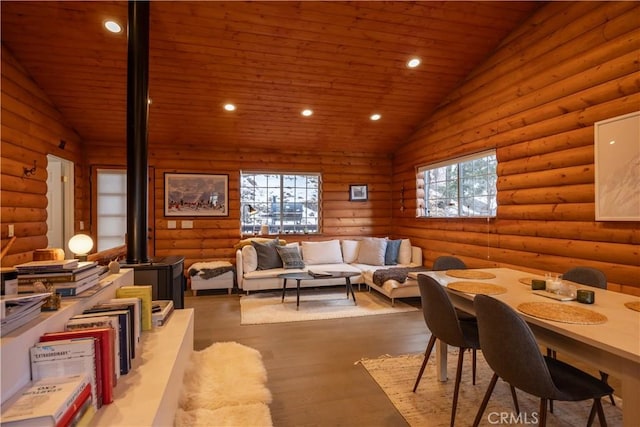 dining room featuring lofted ceiling, rustic walls, wood-type flooring, wooden ceiling, and a wood stove