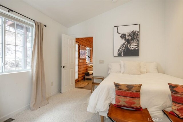 bedroom featuring light colored carpet, vaulted ceiling, and multiple windows