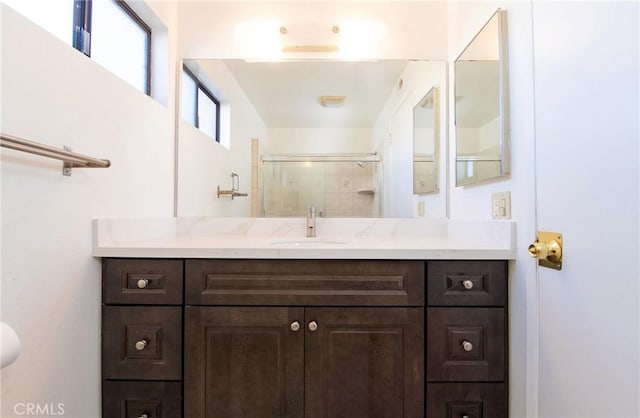 bathroom featuring a shower with door and vanity