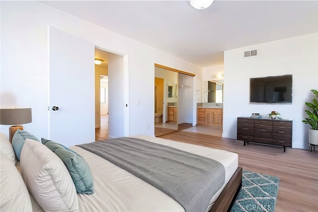 bedroom featuring ensuite bath and wood-type flooring