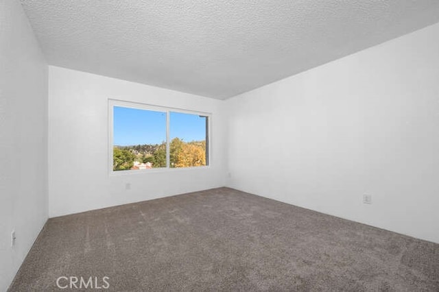 carpeted empty room featuring a textured ceiling