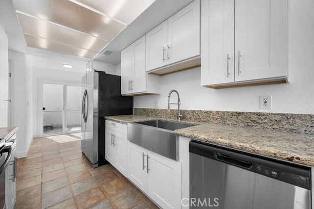 kitchen featuring white cabinetry, appliances with stainless steel finishes, sink, and light stone counters